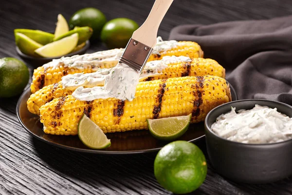 Elote, grilled corn mexican street food , roasted cobs are slathered in sour cream sauce, seasoned with chili powder and sprinkled with cilantro.
