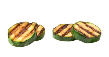 Beyaz arkaplanda ızgara kabak dilimleri var.