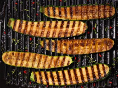 Long slices of grilled zucchini with herbs and spices, top view.
