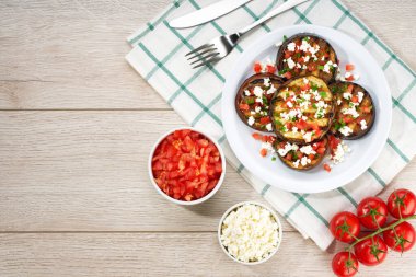 homemade eggplant salad with cheese and tomatoes on a white table, copy space for text.