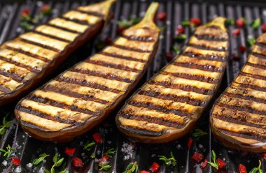 halves grilled eggplants , with chilli pepper and spices. Ideas for barbecues and grill parties.Healthy summer veggie food. Fried eggplant slices in a grill.