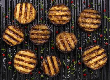 sliced grilled aubergine, with chilli pepper and spices, top view. Ideas for barbecues and grill parties. Healthy summer veggie food. Fried eggplant slices.