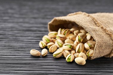 Antep fıstığı siyah bir masanın üzerine torbadan dökülür. Sağlıklı gıda.