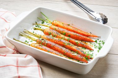 Tahta bir masada seramik formda taze maydanozlu kızarmış havuç. Karamelli havuç. A vitamini bakımından zengin sağlıklı bir havuç tabağı..