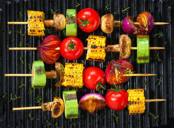 vegetable kebabs on skewers grilled on grill or BBQ with tomatoes, mushrooms, onions, zucchini,corn.  healthy food . vegan or vegetarian food . Grilled vegetarian skewers of colorful vegetables.