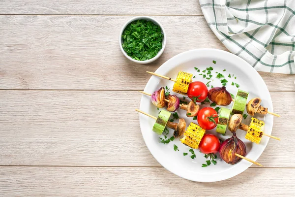 vegetable kebabs on skewers grilled on grill or BBQ  on a white plate, top view. Grilled vegetarian skewers of colorful vegetables.