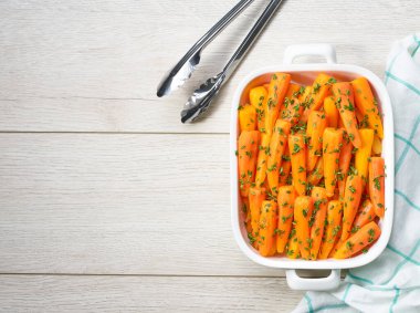 Ahşap bir masada seramik formda kekik ile ballı bebek havuçları, metin için kopyalama alanı. Sağlıklı yaz sebzeleri.