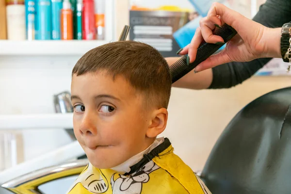 Mały Chłopiec Obcinający Włosy Salonie Fryzjerskim Dziecięcy Fryzjer Nożyczkami Grzebieniem Obrazy Stockowe bez tantiem