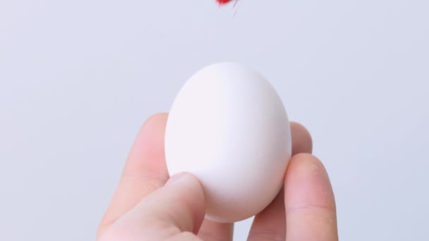 Κοντινό πλάνο ενός ατόμου που βάφει πασχαλινά αυγά με ένα ειδικό πινέλο. Ένα κορίτσι ζωγραφίζει ένα πασχαλινό κόκκινο. Προετοιμασία για το Πάσχα. Λευκό τραπέζι, κοντινό. — Αρχείο Βίντεο