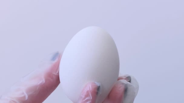 Närbild av en person som målar påskägg med en speciell pensel. En flicka målar ett påskägg grönt och vitt. Förberedelser inför påsk. Vitt bord, närbild. — Stockvideo