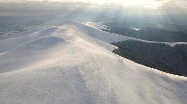 Sisli sıradağlar, çayırlar ve kış mevsiminde karla kaplı tepeler üzerinde inanılmaz bir uçuş. Gymba Dağı, Ukrayna Karpatları. 4k hava görüntüsü.