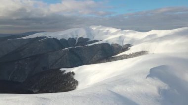 Sisli sıradağlar, çayırlar ve kış mevsiminde karla kaplı tepeler üzerinde inanılmaz bir uçuş. Gymba Dağı, Ukrayna Karpatları. 4k hava görüntüsü.