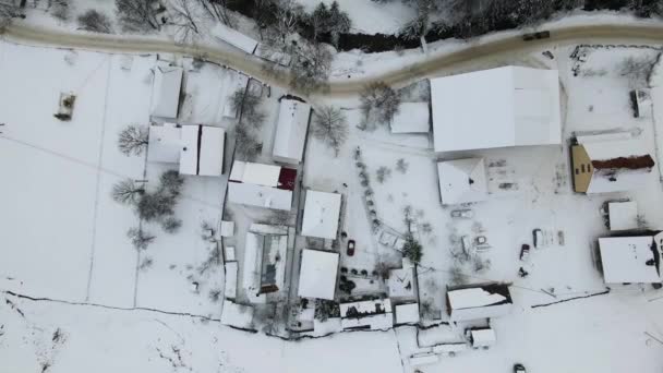 Moving 4K drone flight over the skiing resort village. Aerial winter landscape with small village houses between snow covered forest in cold mountains. — Stock Video