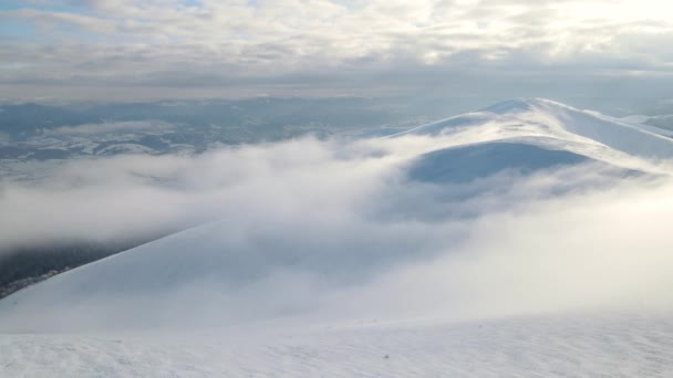 山の峰の上に雲の中を飛ぶ。霧の多い山脈、牧草地、雪の上の素晴らしい航空便は冬の時間にピークをカバーしました。ギンバ山、ウクライナのカルパティア人。4k空中ビュー. — ストック動画