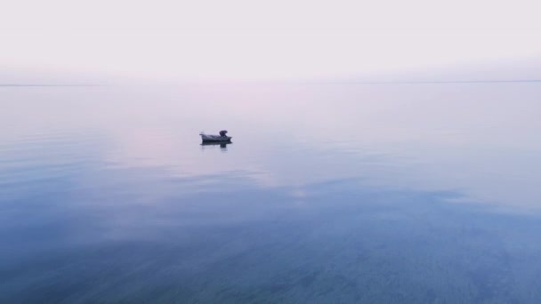 Ένας ψαράς σε μια βάρκα πιάνει ψάρια στη θάλασσα. Πιάνοντας ψάρια του ποταμού από μια βάρκα με κουπιά σε ένα καλάμι ψαρέματος και δίχτυα. Λαθροθηρία. Αθλητική αλιεία στο νερό. — Αρχείο Βίντεο