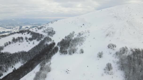 Paesaggio invernale aereo con piccole case rurali tra la foresta innevata in montagne fredde. — Video Stock