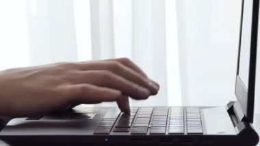 Pencerenin yanındaki masaüstünde dizüstü bilgisayarla çalışan bir adam. Erkek serbest blog yazarı ev ofisinde dizüstü bilgisayarla çalışıyor. İş adamı iş yerinde haberlere göz atıyor