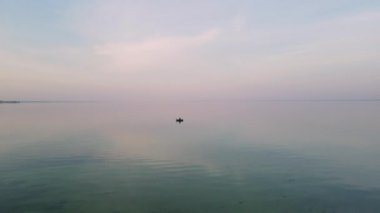 Teknede bir balıkçı denizde balık yakalar. Kürekleri olta ve ağlarla dolu bir tekneden nehir balığı yakalamak. Kaçak avcılık. Suyun üstünde spor balıkçılığı.