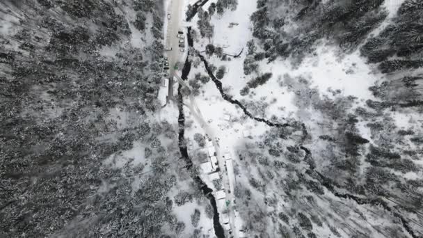 Flygfoto av en skog täckt med snö. Vinterlandskap av kullar täckta med snö. Häpnadsväckande naturlandskap, frusen skog och mörk bergsflod. — Stockvideo