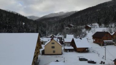 4K insansız hava aracı uçağını kayak merkezi köyüne götürüyoruz. Soğuk dağlarda karla kaplı ormanlar arasında küçük köy evleri olan havadan kış manzarası.