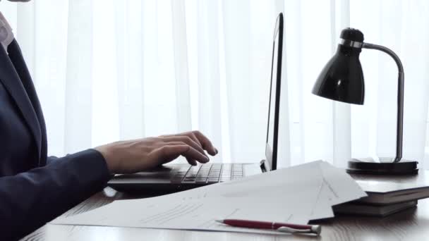 ウィンドウの横にあるデスクトップ上のラップトップで作業している男。自宅のノートパソコンで働く男性のフリーランスブロガー。仕事でオンラインでニュースフィードを閲覧ビジネスマン — ストック動画