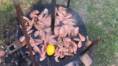 Aşçı ızgaraya soslu karides döker. Kızartma tavasında kızaran kral karideslerinin yakın çekimi. Şef sıcak tavada karides kızartıyor. Yanan arka planda deniz ürünleri