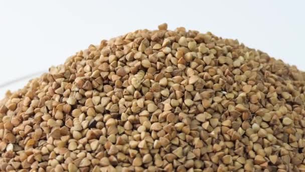 Dry uncooked brown buckwheat groats, rotating buckwheat grains product. Roasted buckwheat kernels. Marketing, advertising use. Studio shot. Healthy organic food diet concept — Wideo stockowe
