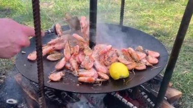 Aşçı ızgaraya soslu karides döker. Kızartma tavasında kızaran kral karideslerinin yakın çekimi. Şef sıcak tavada karides kızartıyor. Yanan arka planda deniz ürünleri