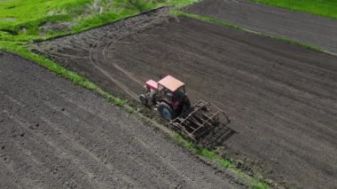 Tarlada tarla sürerken küçük bir traktör tarlası. Tarlada tarla sürme sistemi, toprak izleri, yeni ekin için toprak hazırlama, tarım kavramı, üst görünüm.