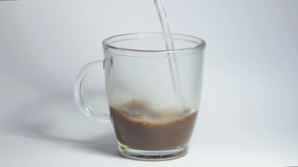 A man brews morning coffee with boiling water close-up. An overhead view of a mug of instant coffee standing on a white table into which a stream of hot water begins to flow. — 비디오