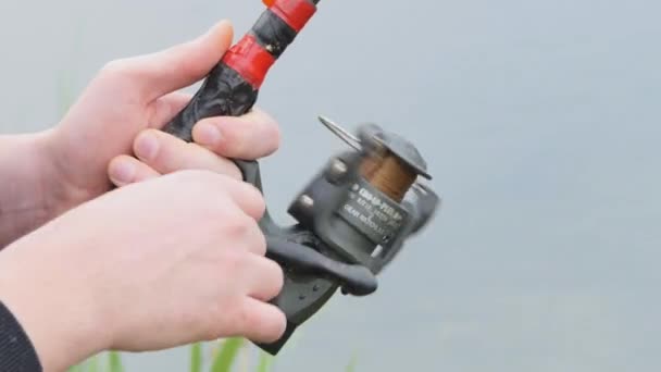Manico a rotazione con mulinello da pesca. Maschio pescatore hobby pesca sul fiume stringe la bobina della lenza del pesce estate. — Video Stock