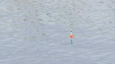 Nehirde oltayla balık tutarken dalgalarda sallanan kırmızı ve yeşil bir balıkçı teknesinin yakın çekimi..