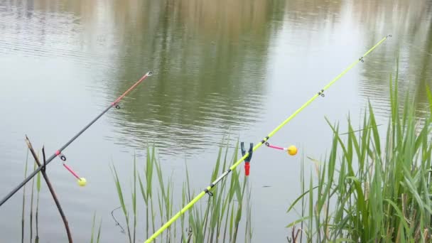 A colored rattle for biting is put on a fishing rod while fishing. Bite signal at the tip of the rod. The bite alarm will alert you to a bite. Fishing tackle close-up. — Video