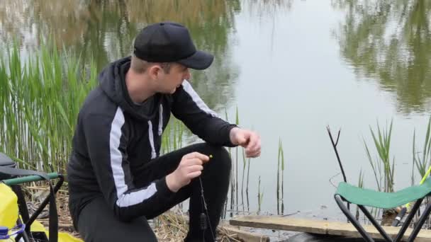 Fisherman loads the bait in the feeder tackle for fishing. Spring fishing. — Stockvideo
