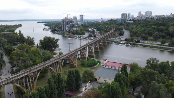 Europes unique arched railway bridge over the Dnieper River with a lively embankment and yacht club under it Aerial view of the old arched railway Merefo-Kherson bridge in the city of Dnipro. — Stock video