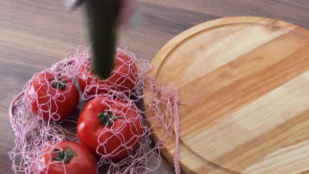 A woman takes out cucumber tomatoes from a reusable grocery bag vegetables on a table in the kitchen at home after shopping for groceries. Waste-free and plastic-free concept. Mesh cotton shopper. — 비디오