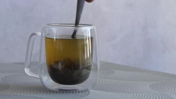 Genomskinlig kopp te. Manlig hand blandar socker med te. Traditionellt te. — Stockvideo