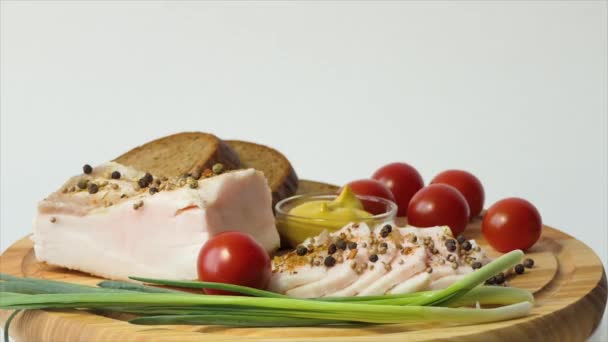Chopped lard on a cutting board A large piece of lard with skin and sprinkled with red pepper and spices. Mustard, cherry tomatoes, garlic, green onions, black bread. — Αρχείο Βίντεο