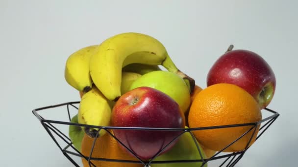 Obrotowy kosz owoców ze świeżymi bananami, jabłkiem, pomarańczą i grejpfrutem dla zdrowego stylu życia. Mężczyzna bierze jabłko z kosza owoców. Witaminy w owocach. Koncepcja zdrowej żywności. — Wideo stockowe