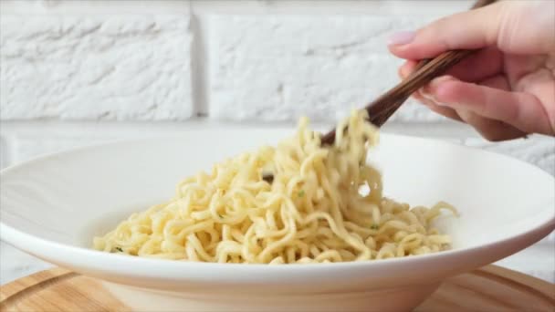 Fast food pâtes close-up. nouilles instantanées dans un bol à soupe avec des baguettes chinoises. — Video