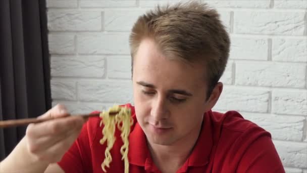 Un uomo mangia vermicelli, pasta fast food. Il tipo mangia spaghetti divertenti. Primo piano — Video Stock