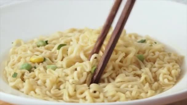 Snabbmatspasta närbild. Omedelbara nudlar i en soppskål med kinesiska ätpinnar. — Stockvideo