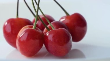 Taze olgun kiraz yakından. Dönüşümlü organik kırmızı kirazlar beyaz arka planda izole edilmiş. Böğürtlenler dönüyor. 4K video