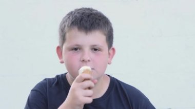 Küçük şişman çocuk sokakta dondurma yiyor. Tatmin olmuş yüz ifadesi. 4 bin.