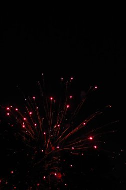 Kırmızı, koyu arkaplanda havai fişekleri ateşler. 