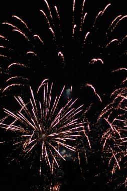 Kırmızı, koyu arkaplanda havai fişekleri ateşler. 