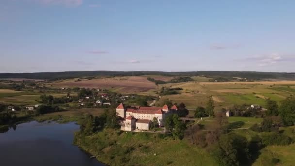Vue aérienne d'un drone d'un château historique sur une colline près d'un lac, d'une architecture médiévale et d'un point de repère culturel dans la campagne de Svirzh, près de Lviv, en Ukraine, par une chaude journée d'été ensoleillée. Attractions touristiques et touristiques. — Video