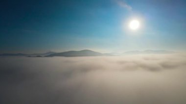 Gün doğumunda dağlarda sis var.