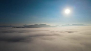 Gün doğumunda dağlarda sis var.