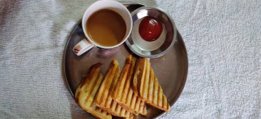 Kızarmış ekmek, füme jambon, peynir, domates ve marul tabakta servis edilir. 